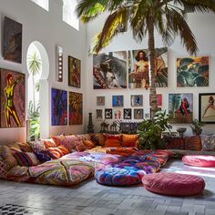 a living room filled with lots of colorful pillows and art on the wall above it