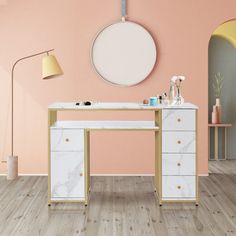 a white marble desk with gold legs and drawers in a pink room, with an oval mirror on the wall above it