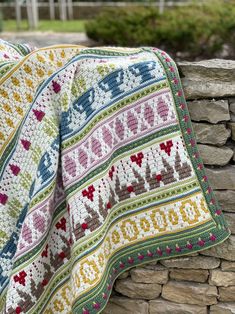 a crocheted blanket sitting on top of a stone wall