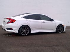 a white honda civic parked in front of a brick wall with black rims on it