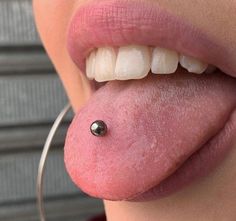 a close up of a person's tongue with a piercing on it