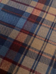 a close up view of a plaid pattern on a fabric material that is blue, red and tan