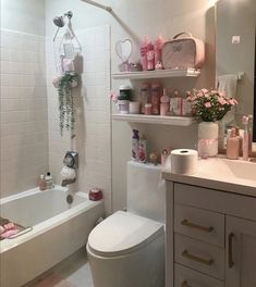 the bathroom is decorated in pink and white with lots of flowers on the shelf above the toilet