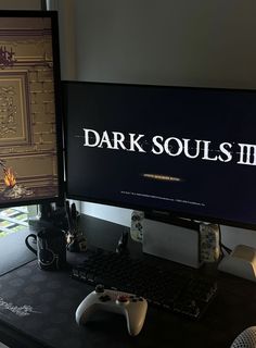 two computer monitors sitting next to each other on top of a desk with a game controller