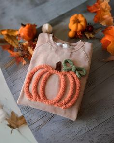 a baby's shirt with a pumpkin applique on it