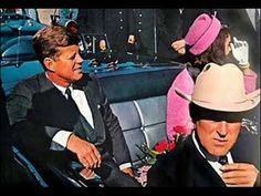 two men in suits and hats sitting next to each other on a car with pink flowers