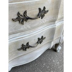 an antique white dresser with metal handles