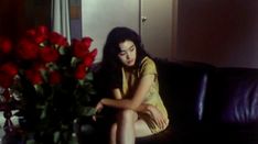 a woman sitting on top of a couch next to a vase filled with red roses