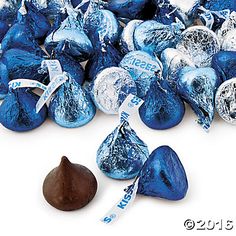 a pile of blue and silver foiled candies next to a piece of chocolate