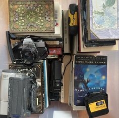 there are many books, cameras and other items on the table together in this room