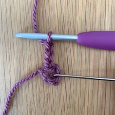 two crochet hooks are hooked up to the end of a hook on a wooden surface