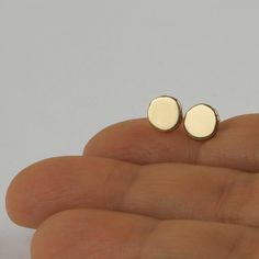 "Shiny round gold 14k stud earrings, simple and perfect for every day's wear. These gold earrings are handmade of yellow 14k solid gold. I melted the gold into a ball, and then hammered each ball to its irregular shape. No two are ever identical, and each has a unique and organic look. The edges of the pebbles are rough, while the flat surface has a smooth shiny finish. These are classic \"wear with everything\" gold earrings - a perfect gift, or a treat for you. Earrings diameter is approx 7 mm Minimalist 14k Gold Filled Circle Earrings, Hypoallergenic Round Earrings In Recycled Gold, Dainty Recycled Gold Earrings, Minimalist Yellow Gold Earrings For Gift, Minimalist Rose Gold Circle Earrings, Minimalist Round Earrings With Simple Design, 14k Gold Circle Earrings For Gifts, Dainty Circle Earrings In 14k Gold, Minimalist Everyday Earrings In Recycled Gold