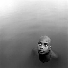 a black and white photo of a man in the water with his head above the water's surface