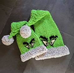 two green knitted hats with eyes on them