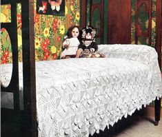 a doll sitting on top of a bed next to a black dog and a white crocheted bedspread