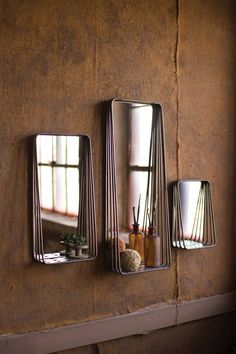 three mirrors mounted to the side of a wall