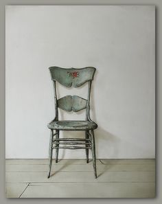 an old chair sitting in front of a white wall with a flower painted on it