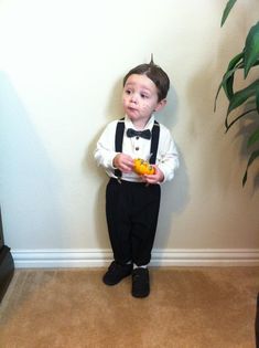 a young boy in a white shirt and black bow tie is holding an orange slice