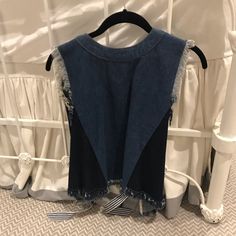 the back of a denim vest hanging on a clothes rack