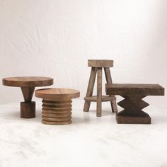 three wooden stools and one table on a white surface