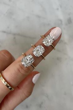 a woman's hand with three diamond rings on it