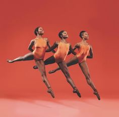 three women in orange leotards are jumping and posing for the camera with their legs spread out