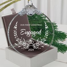 a christmas ornament in a box on a table with greenery and decorations