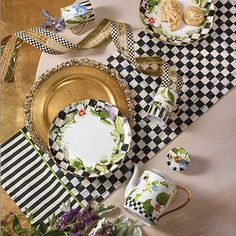 the table is set with black and white checkered placemats, plates, cups, and napkins