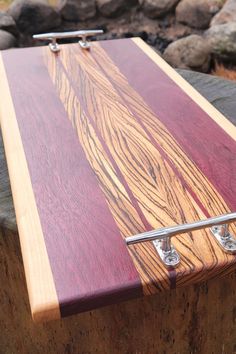 a close up of a wooden board with metal handles on a tree stump in front of some rocks