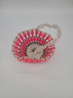 a pink and white hand fan on a chain