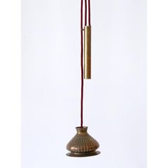 a brown vase with a red cord hanging from it's side and an object in the background