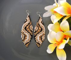 a pair of beaded earrings next to a flower