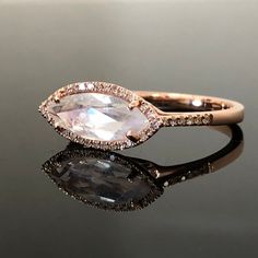 14K Moonstone and Diamond Ring METAL: 14K Rose Gold TOTAL WEIGHT: 2.1 g (approximate, varies per size) MOONSTONE: Marquise Cut Rainbow Moonstone DIMENSIONS: 12mm x 4mm TOTAL WEIGHT: 1.15 ct DIAMONDS: Round Brilliant Cut Diamonds COLOR: G/H CLARITY: VS2-SI1 TOTAL WEIGHT: 0.11 ct SIZE: Ladies Size 6 1/2 DESCRIPTION: This ring is so much more beautiful in person. It has a marquise cut rainbow moonstone, prong set and with a diamond pave halo. The shank also as some diamonds pave set for extra spark Luxury Moonstone Ring With Rose Cut Diamonds For Promise, White Marquise Rose Cut Diamond Jewelry, Fine Marquise Moonstone Ring For Anniversary, Fine Jewelry Marquise Moonstone Ring For Anniversary, Marquise Moonstone Ring For Anniversary, Marquise Rose Gold Diamond Ring With Gemstone, Rose Gold Marquise Diamond Ring With Gemstone, Luxury Moonstone Halo Ring For Wedding, Marquise Rose Gold Diamond Ring