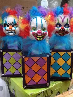 three colorful clown heads sitting on top of a green box with red, yellow and blue hair