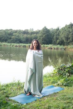 a woman standing on top of a blue mat next to a lake