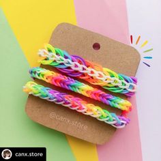 three rainbow loom bracelets on top of a cardboard box with a tag attached to it