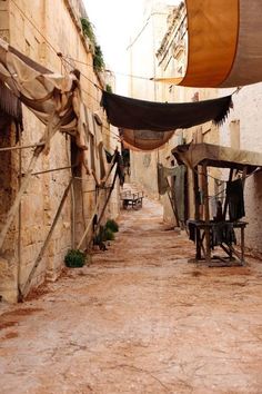 an alley way with clothes hanging on the line and wooden benches in front of it