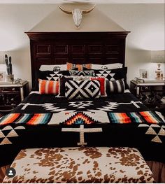 a bed with pillows and blankets on it in a bedroom next to two nightstands