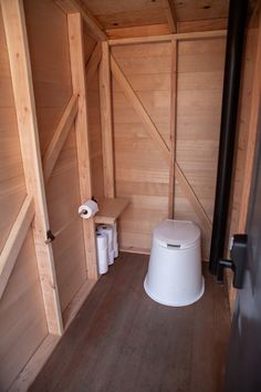 there is a toilet in the corner of this small room with wood paneling on the walls