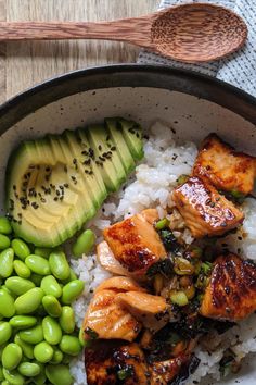 a bowl filled with rice, meat and vegetables next to an avocado slice