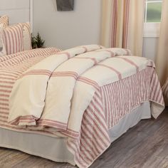 the bed is made with red and white striped comforter, pillows, and curtains