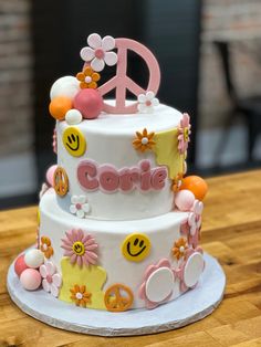 a three tiered cake decorated with flowers and peace signs