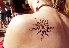 the back of a woman's shoulder with a sun tattoo on it