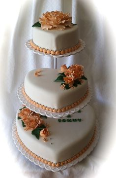 three tiered wedding cake with flowers on the top and bottom, sitting on a white tablecloth