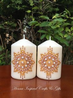 two white candles decorated with gold and pearls