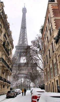 the eiffel tower is in the distance as people walk down a snowy street