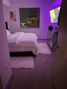 a bedroom with purple lighting and a white bed