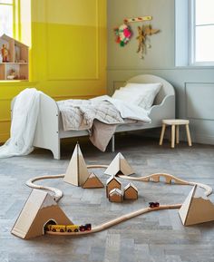 a child's bedroom with a train set and toy cars on the floor in front of it