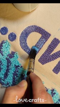 someone is painting the letters on a t - shirt with crocheted yarns