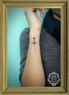 an anchor tattoo on the wrist is shown in a gold frame with a blue background